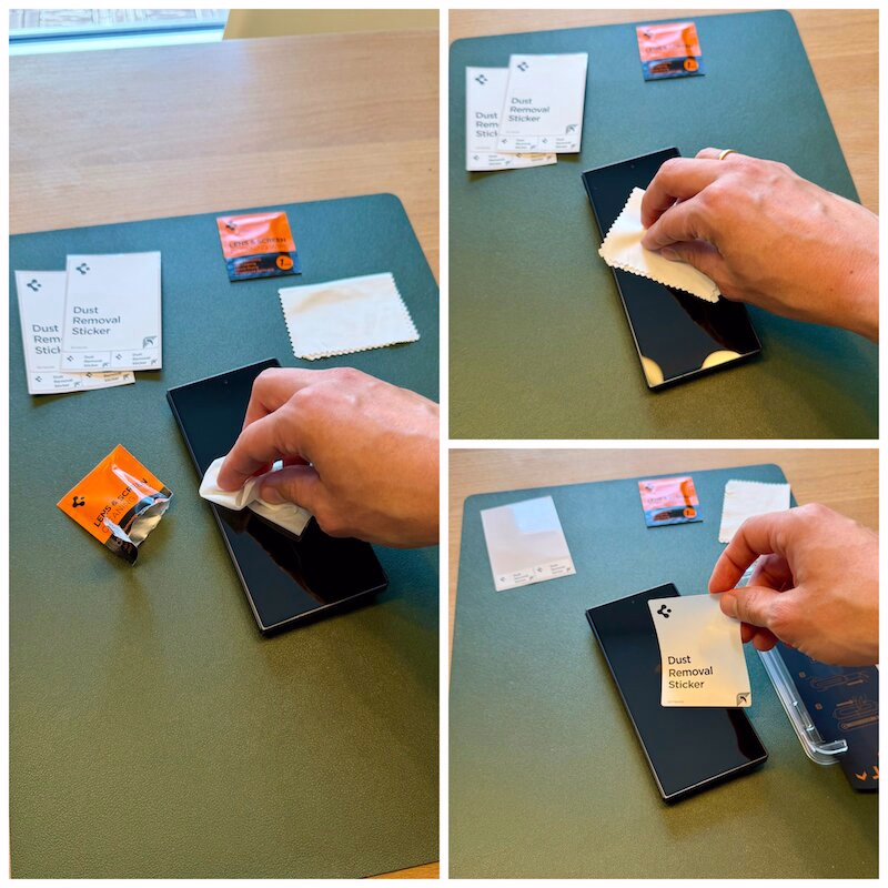 galaxy_fold_8_ultra_spigen_panzerglas_schutzglas_glastr_ezfit_vorbereitung - smartphonehuellen-test.de Auf einem grünen Schreibtisch bringen Hände einen Staubentfernungsaufkleber auf einem Smartphone an; daneben liegen ein Reinigungstuch und kleine Päckchen. Davor wird mit einem Alkoholtuch das Display gereinigt und dann mit Mikrofaser getrocknet.